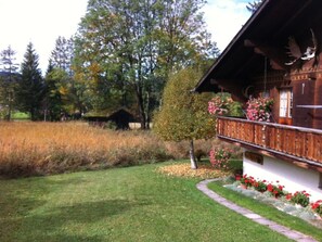 A wooden cabin with a balcony, surrounded by a well-maintained lawn and flowering plants. - Chalet Nyati, (Gstaad), by Interhome (Gstaad)