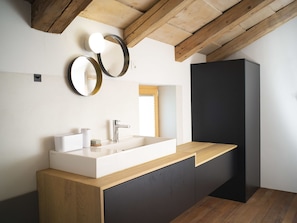 Un baño moderno con techo de madera, un lavabo blanco y dos espejos fijos a la pared.