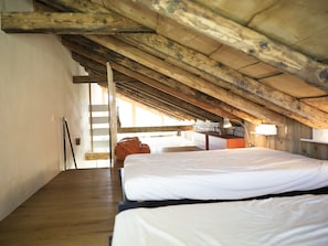 Una habitación con vigas de madera, una cama, un escritorio y un ventanal.
