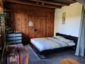 Une chambre à coucher comprenant un lit, une commode, un banc et une armoire en bois.