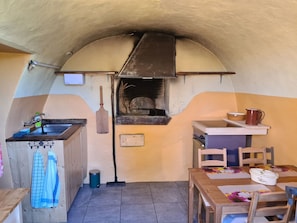 Een praktische keuken met een inbouwoven, een spoelbak en een klein eethoekje met een tafel en stoelen.