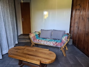 Une pièce avec un banc en bois, un canapé coloré et une porte.