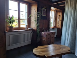 Une pièce chaleureuse avec une table en bois, un radiateur et une fenêtre donnant sur un beau paysage.