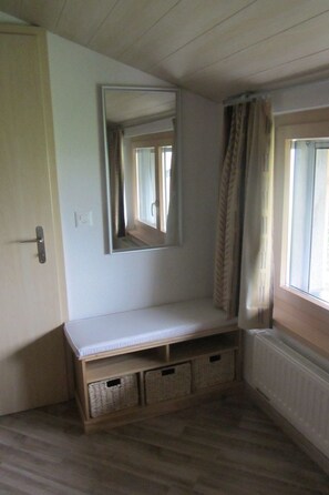 Ein Zimmer mit eingebautem Sitzplatz, einem Spiegel, einem Heizkörper und einem mit Vorhängen versehenen Fenster.