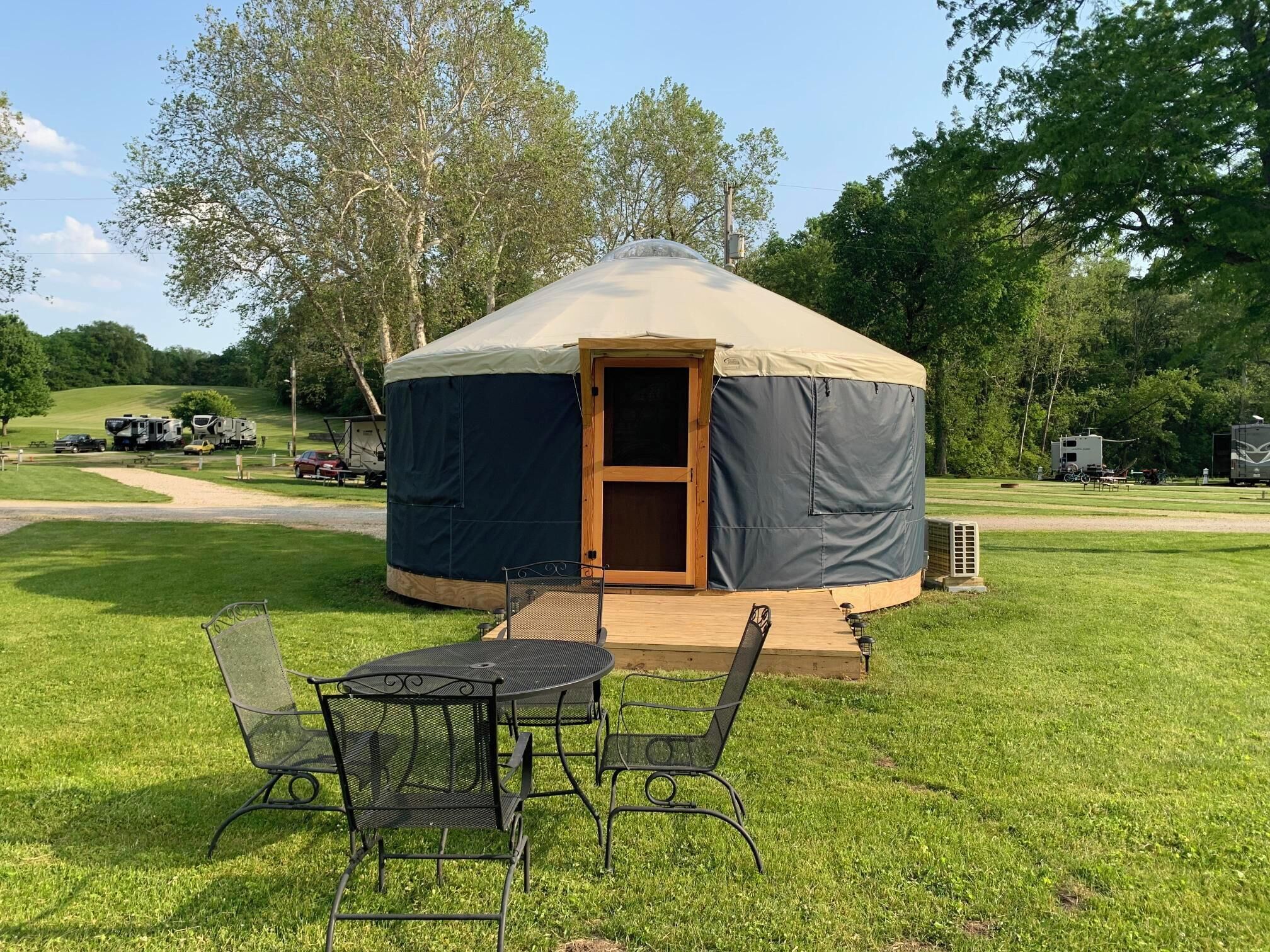 A yurt with a covered entrance, a small porch, and a seating area with chairs and a table.