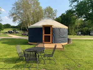 A yurt with a covered entrance, a small porch, and a seating area with chairs and a table.