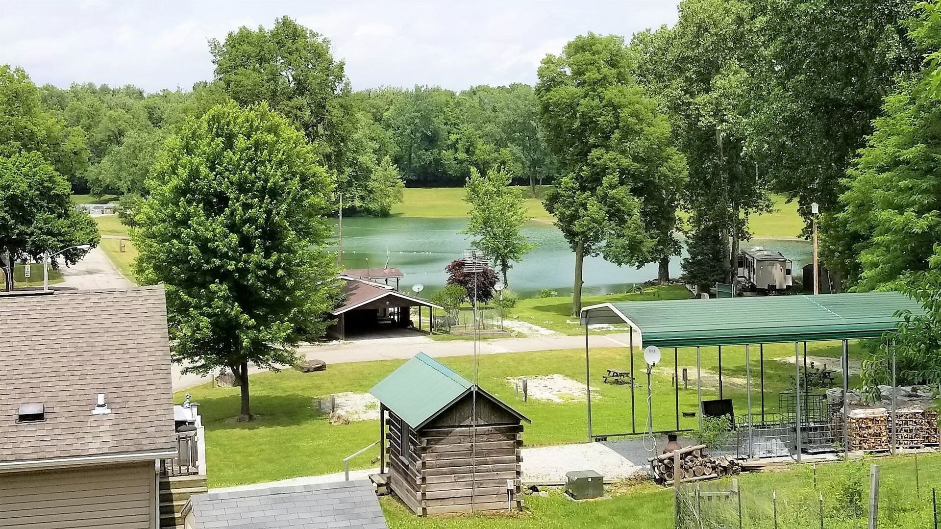 A lakeside cabin with a covered porch, a small shed, and a picnic table.