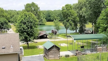 Una cabaña junto al lago con un porche cubierto, un cobertizo pequeño y una mesa de picnic.