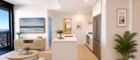 A modern apartment with a living area, kitchen, and a balcony with a city view.