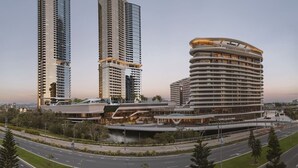 Un área urbana moderna con rascacielos, un hotel de diseño curvo y una red vial bien conservada.
