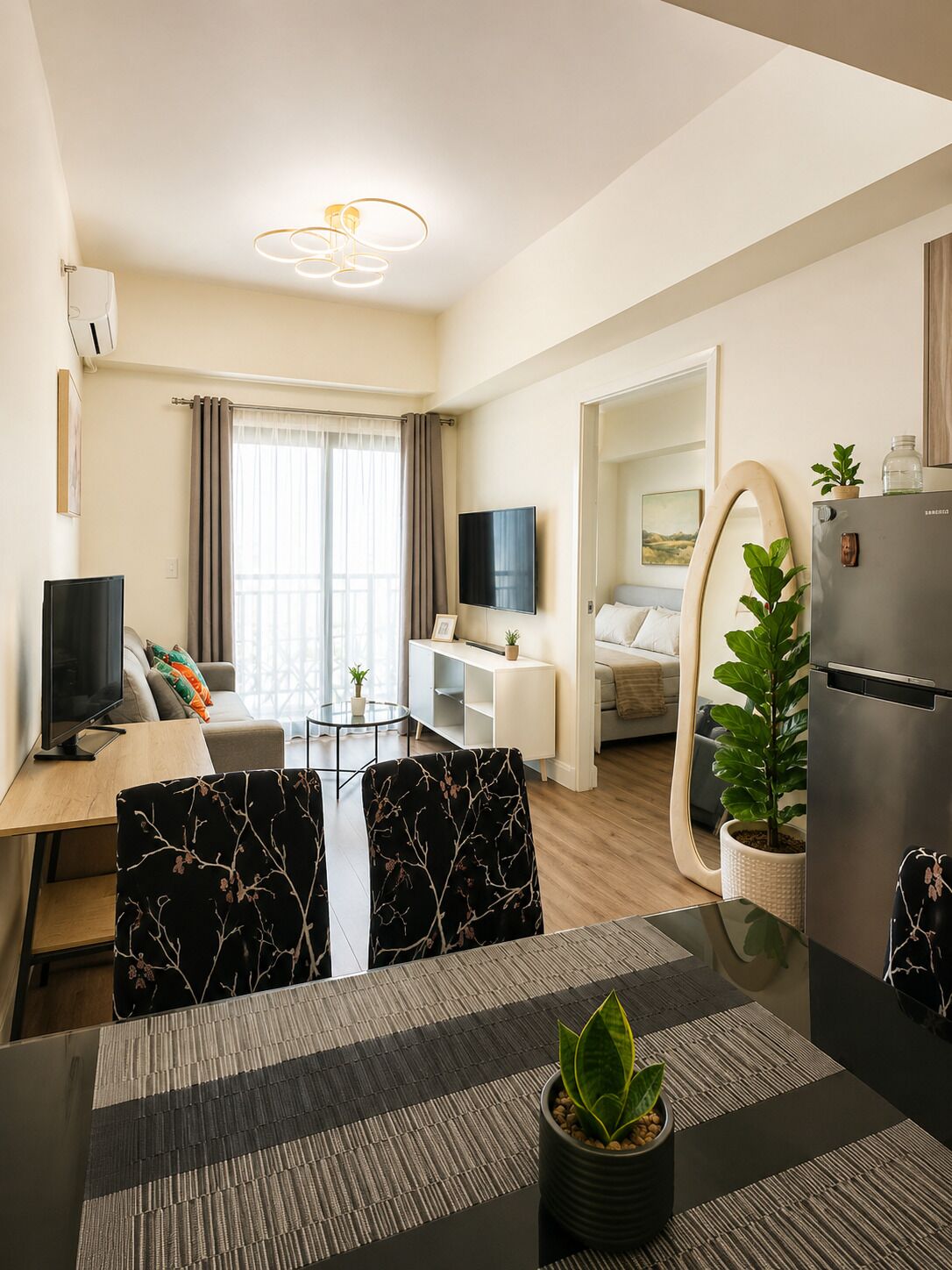 Een moderne woonkamer met een eethoek, een televisie en een koelkast.