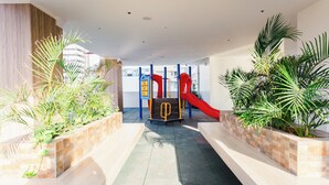 A children's play area with a slide, surrounded by planters and a tiled floor. - Cozy 1-bedroom condo, Wifi, Pool, Netflix, near IT Park (Cebu City)