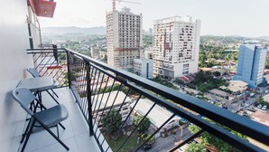 A balcony with a view of a cityscape, including buildings and construction cranes. - Cozy 1-bedroom condo, Wifi, Pool, Netflix, near IT Park (Cebu City)