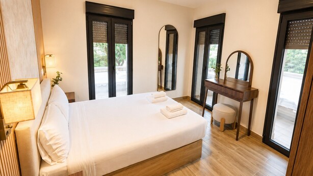A hotel room with a large bed, a wooden desk, a mirror, and a view of the outdoors. - Flat Near Metro, Madrid (Madrid)