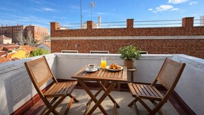 A rooftop terrace with a wooden table, two chairs, a plate of croissants, a glass of orange juice, and a potted plant. - Flat Near Metro, Madrid (Madrid)