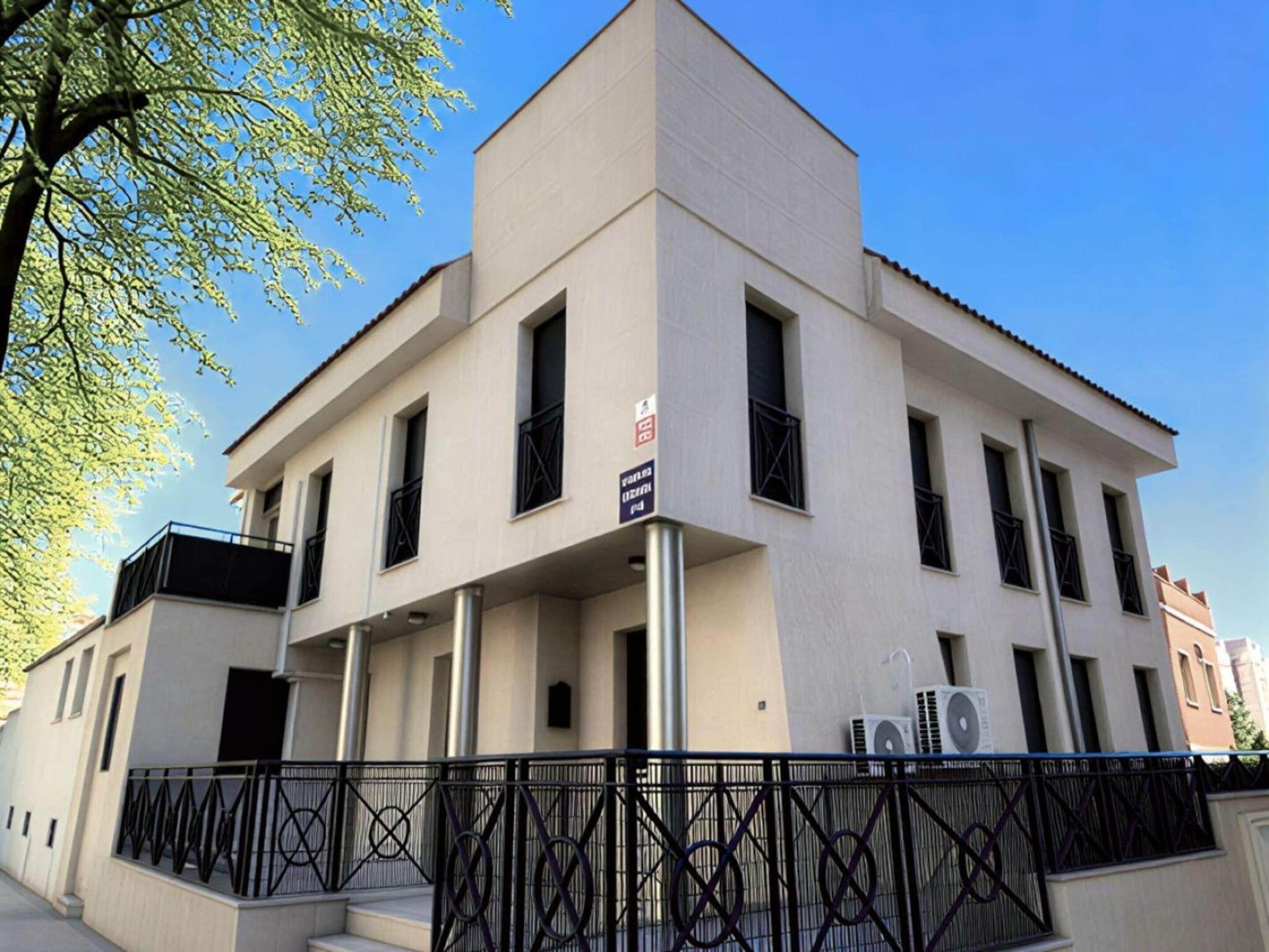 Un edificio moderno con techo plano, varias ventanas y una cerca de metal.