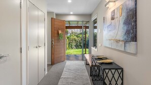 Un couloir avec une porte en bois, un banc, une console et un tableau accroché au mur.