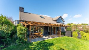 Une maison moderne dotée d’un patio couvert, d’un garage apparent et d’un jardin bien entretenu.