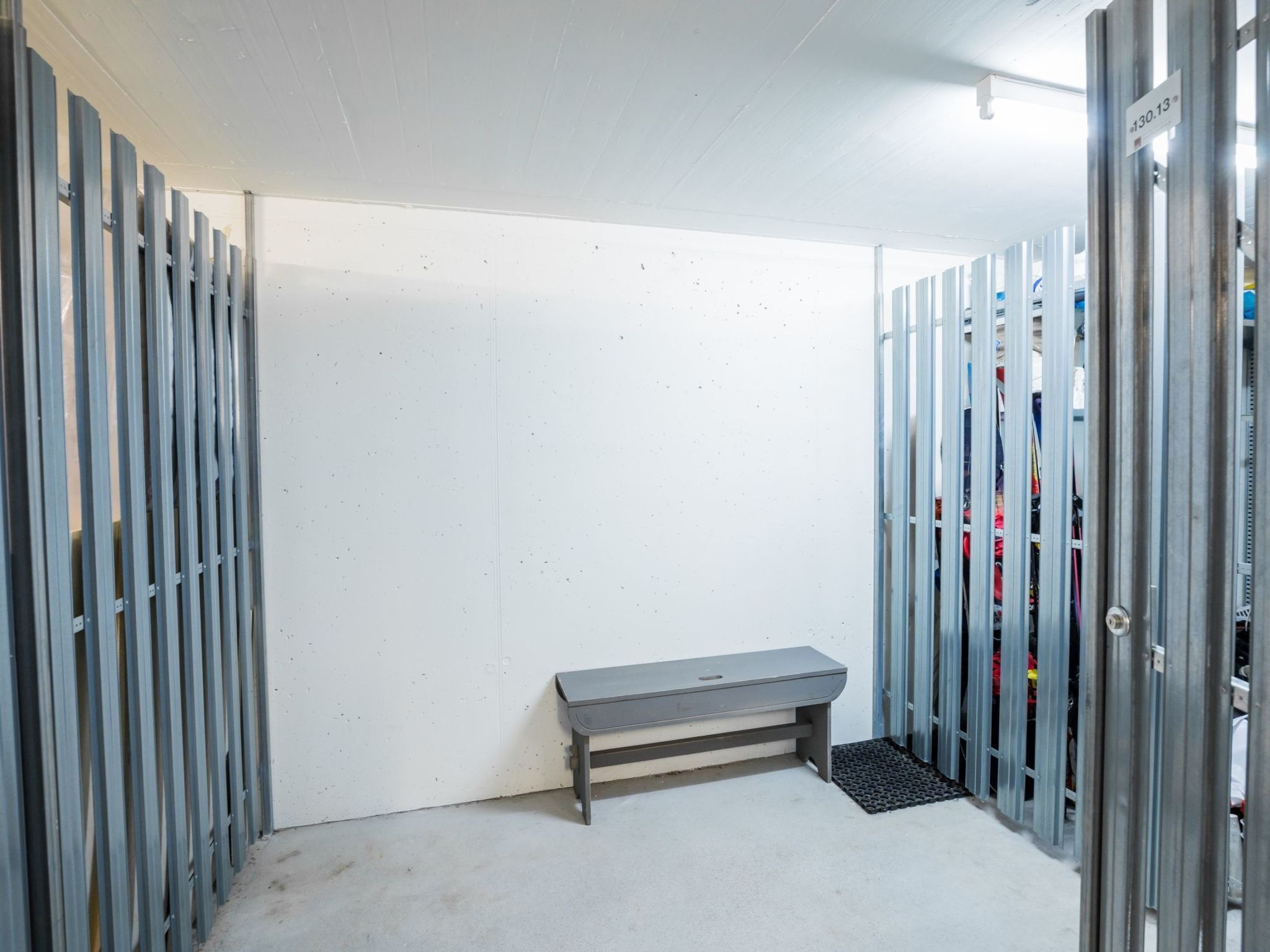 Een kamer met een bank, metalen kasten en een witte muur.