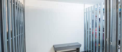 Een kamer met een bank, metalen kasten en een witte muur.