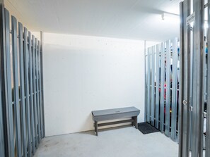 Une pièce avec un banc, des casiers métalliques et un mur blanc.