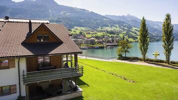 Une maison avec un balcon donnant sur un lac et des montagnes.