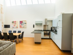 A modern kitchen with a dining area, featuring a table, chairs, and a sofa.