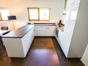 Una cocina moderna con armarios blancos, encimera de granito, horno integrado y una ventana sobre el fregadero.