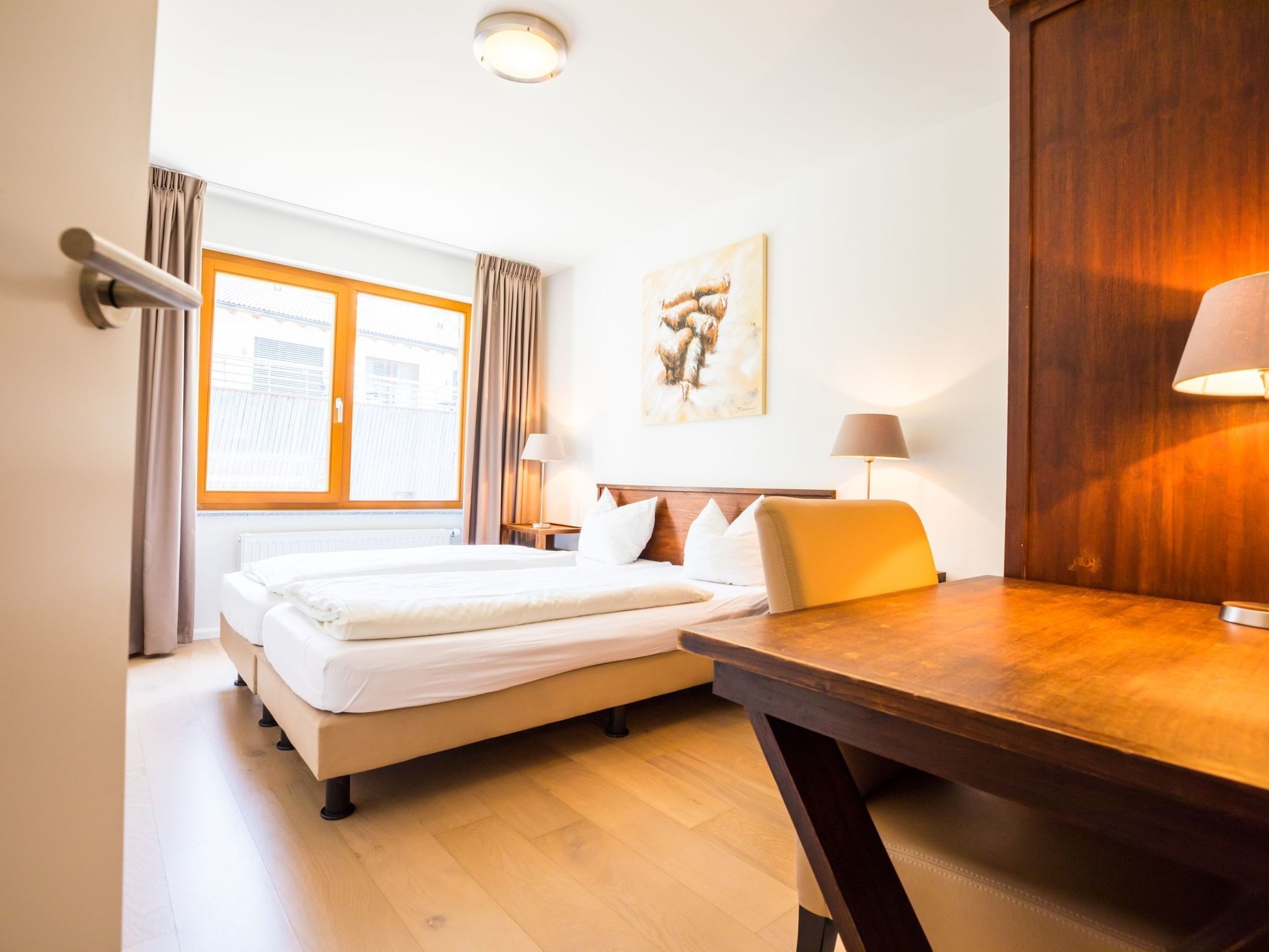 A hotel room with a bed, a desk, and a window with curtains.