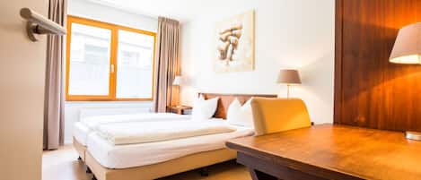 Ein Hotelzimmer mit einem Bett, einem Schreibtisch und einem fenster mit Vorhängen.