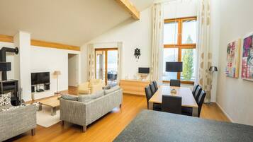 Un salon moderne avec une cheminée, un canapé, une table à manger et de grandes fenêtres.