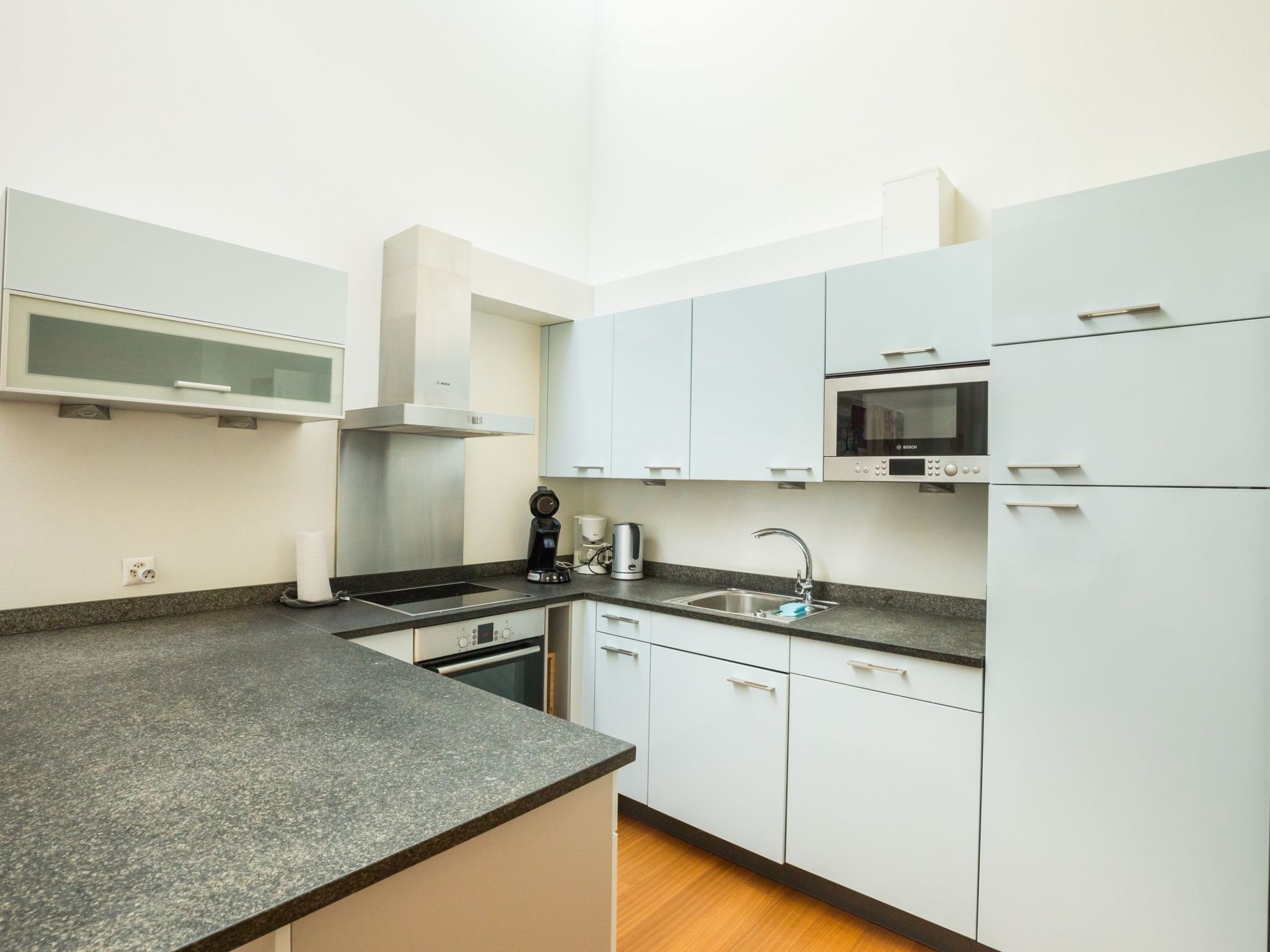 A modern kitchen with white cabinets, a Bosch microwave, and a built-in oven.
