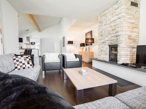 A modern living room with a stone fireplace, a sofa, a coffee table, and a dining area.