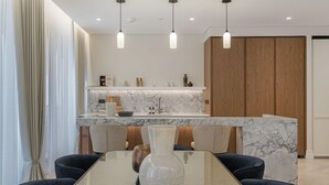 Une cuisine moderne dotée d’un plan de travail en marbre, de meubles en bois et de luminaires suspendus.
