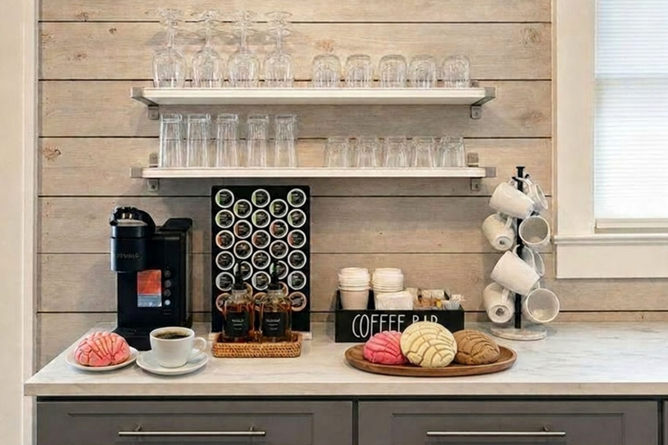 A kitchen counter with a coffee maker, mugs, and a coffee bar sign.