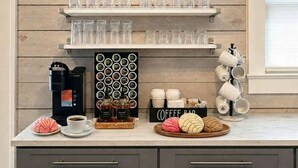 En køkkenbordplade med kaffemaskine, krus og et skilt med 'coffee bar'.