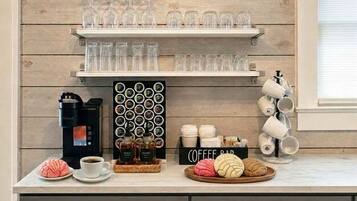 A kitchen counter with a coffee maker, mugs, and a coffee bar sign.