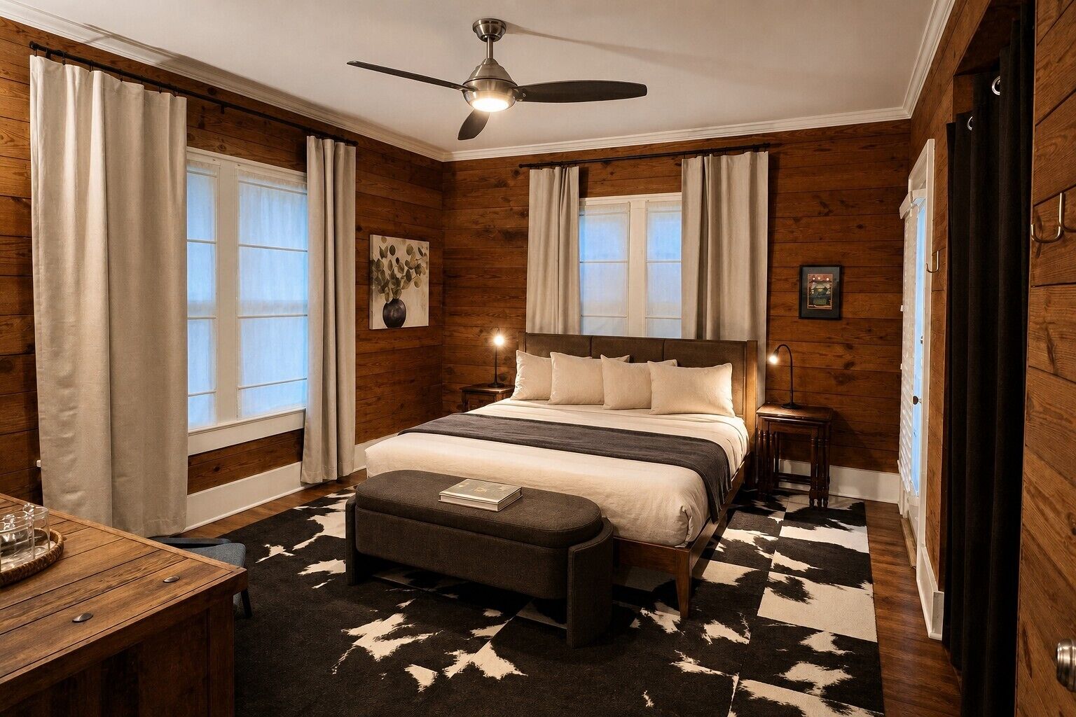 A bedroom with a bed, a desk, a chair, a ceiling fan, and a rug.