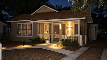 A two-story house with a covered porch and a well-lit front yard.