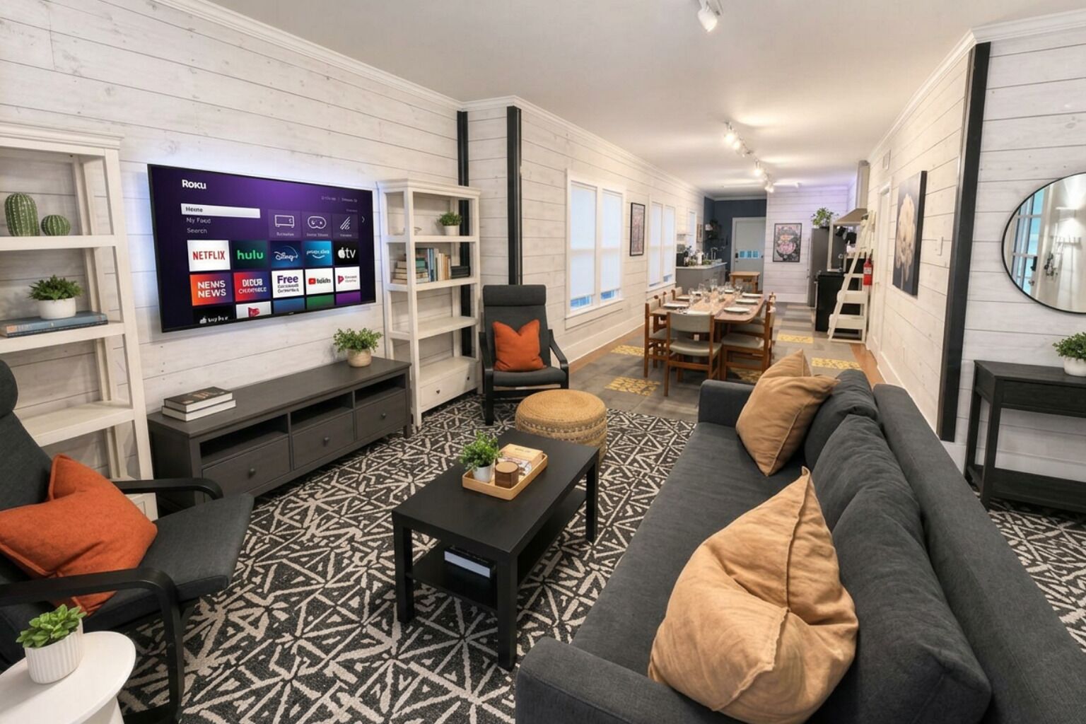 Uma sala de estar moderna com televisão de tela plana, um sofá, uma mesa de centro e um tapete estampado.