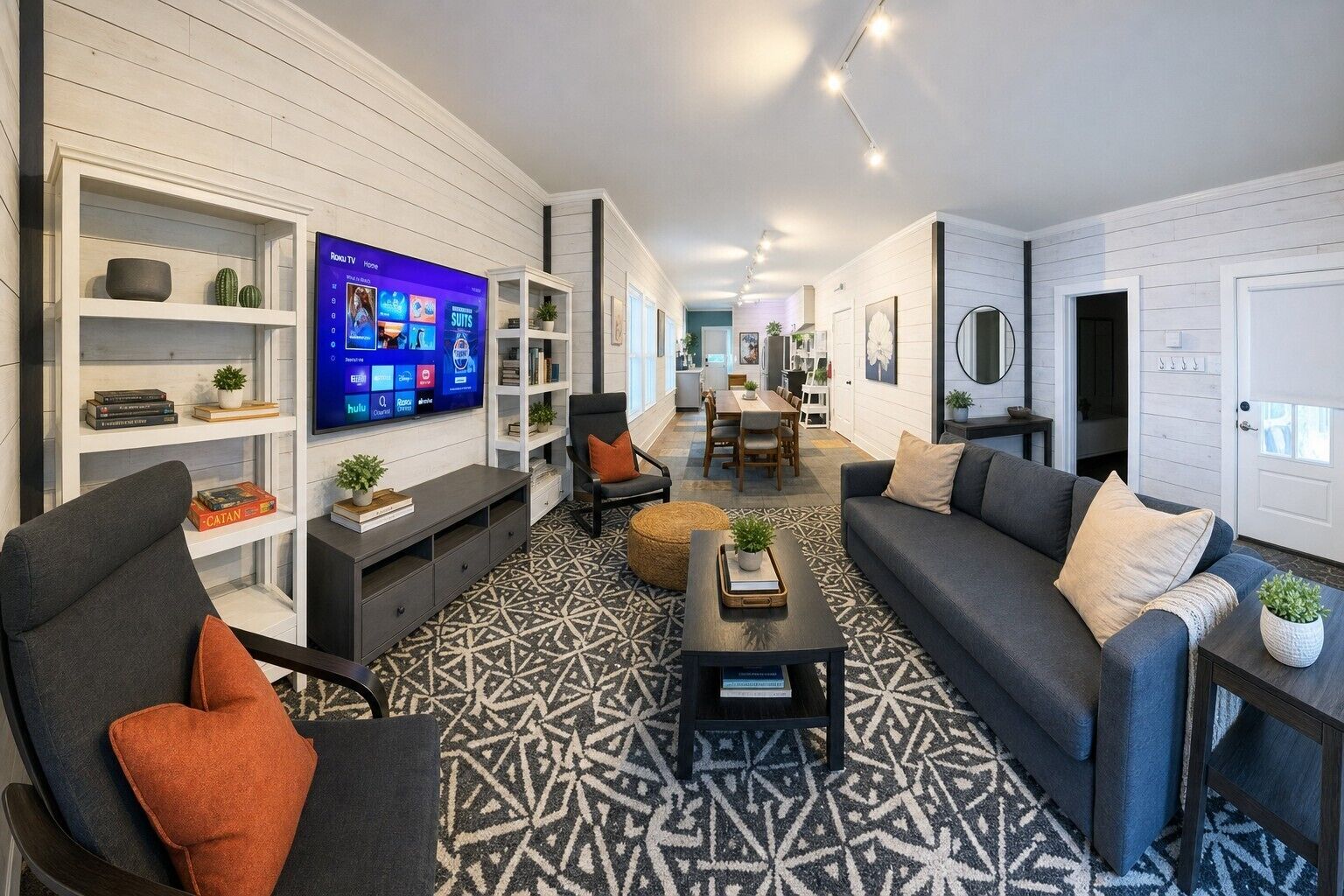 Uma sala de estar moderna com uma televisão de tela plana, um sofá, uma mesa de centro e um tapete estampado.