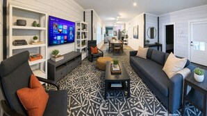 En moderne stue med et fladskærms-tv, en sofa, et sofabord og en tæppe med et mønster.