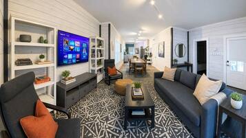 A modern living room with a flat-screen TV, a sofa, a coffee table, and a patterned rug.