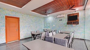 Une salle de conférence dotée d’une porte en bois, d’un ventilateur de plafond et d’un téléviseur fixé au mur.