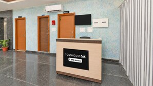 Un comptoir d’accueil avec une enseigne indiquant « TOWNHOUSE OAK » et une étiquette « YO-Serviced ». On y trouve deux portes en bois portant l’inscription « CUISINE » et un téléviseur fixé au mur.