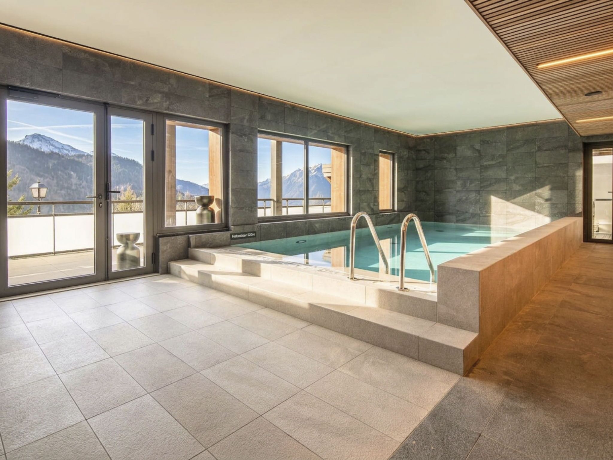 Una piscina interior moderna con ventanas amplias y vistas a las montañas.