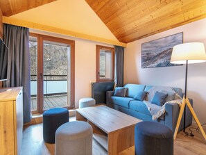 En moderne stue med træloft, sofa, skottomaner, et sofabord og et billede på væggen.