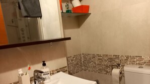 Un bany amb un lavabo, dues vàteres, un mirall i una repisa amb tovalloles.