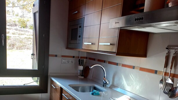 Una cuina moderna amb armaris de fusta, un rentamigles d'acer inoxidable i un forn integrat.
