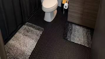 A bathroom with a shower, toilet, sink, and mirror.